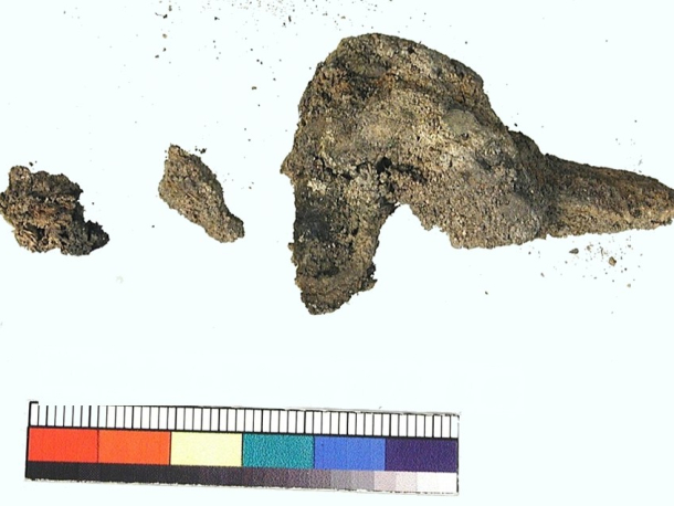 Stříbrná spona zdobená zlaceným terčíkem se skleněným kamenem, mladší doba římská. Stav před konzervací.