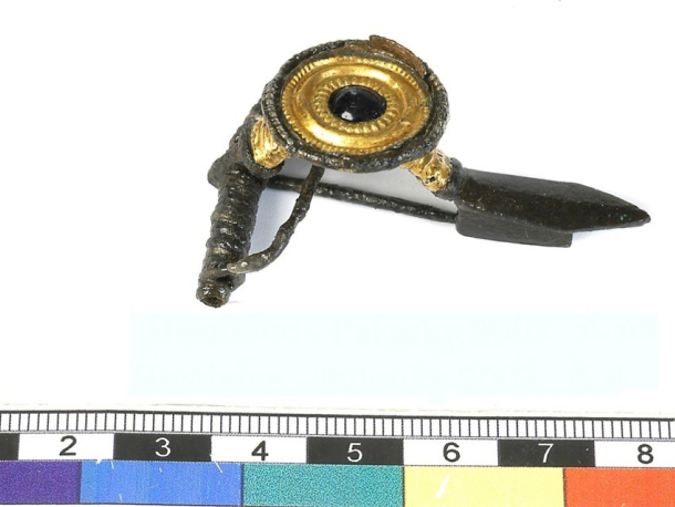 Stříbrná spona zdobená zlaceným terčíkem se skleněným kamenem, mladší doba římská. Stav po konzervaci.